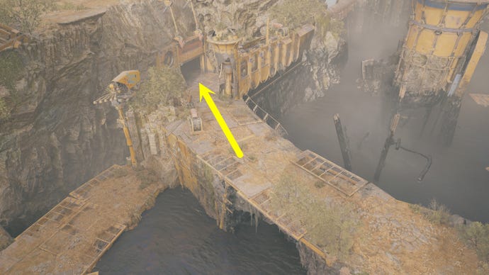 An aerial view of Derelict Dam on Koboh in Jedi: Survivor, with an arrow pointing to a nearby cave entrance.