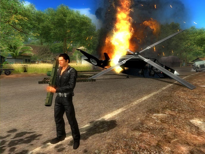 A man holds a rocket launcher in front of a helicopter on fire in Just Cause