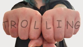 Outstretched fists displaying a mock-up knuckle tattoo: TROLLING.