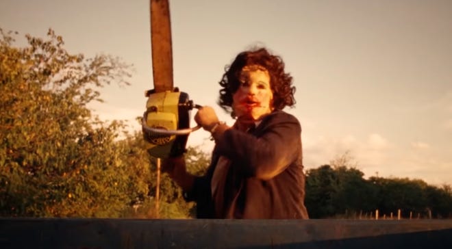 Still image of Leatherface wielding a chainsaw