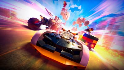 Lego 2K Drive promo art showing a Lego car racing toward the camera, with a variety of other Lego vehicles around it