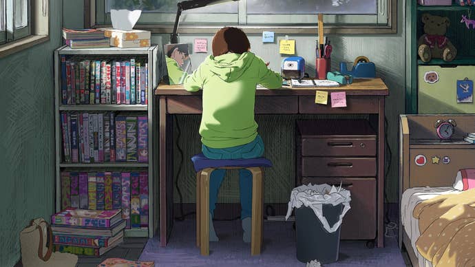 A girl in a green hoodie sits at a desk and draws comics.
