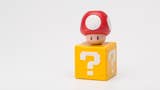 A cute, plastic modelled replica of a yellow Mario question box with a red and white mushroom sat on top of it.