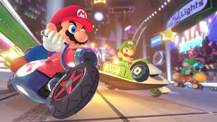 In Mario Kart 8, Mario on a motorcycle leans into a turn ahead of Luigi in a green kart
