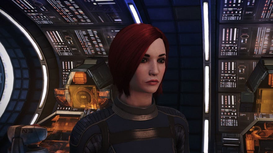 Commander Shepard stands facing the camera on the deck of the Normandy in Mass Effect, banks of cool orange computers behind her.