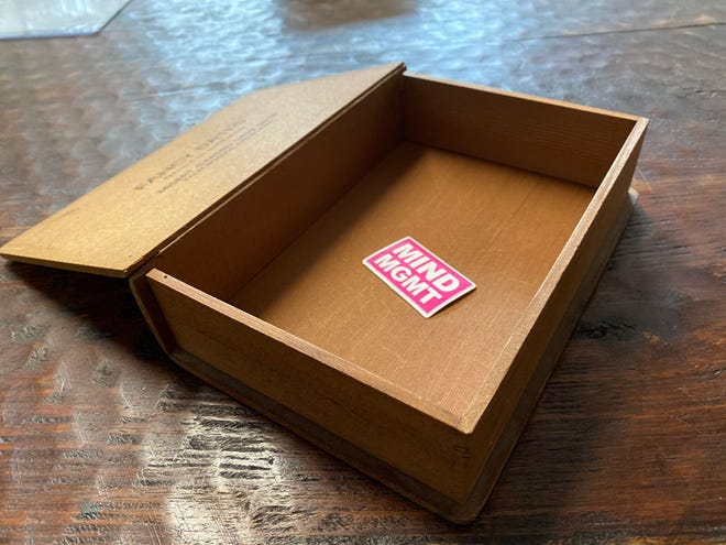 Photo of an open wooden box featuring a sticker that reads Mind MGMT