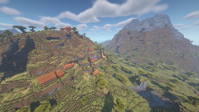 Un sat Minecraft construit pe partea unui deal Savanna, cu un munte mare cu vârf de piatră în fundal