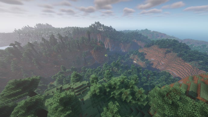 A Minecraft landscape of winding hills and valleys covered in forest.