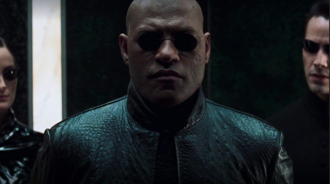 Lawrence Fishburne wearing sunglasses and a leather jacket as Morpheus
