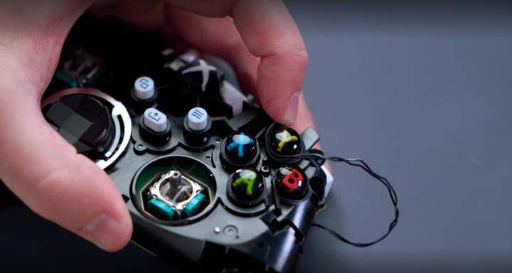A picture of an Xbox controller with the shell taken off and a hand in frame holding parts of it together.