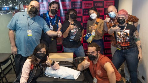Photo featuring Povperse team in office at NYCC looking at camera with thumbs up