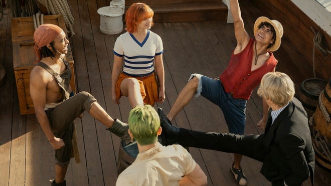 Cast from the One Piece live action strike a stylish pose, where they stand in a circle, raise one leg and touch each others' foot.