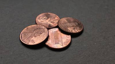 Four pennies in a pile on a dark gray surface