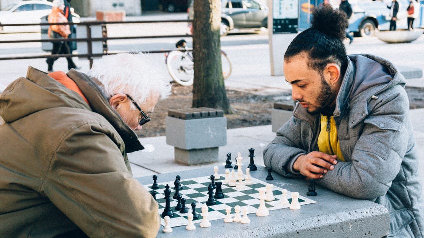 Two people playing chess in a park