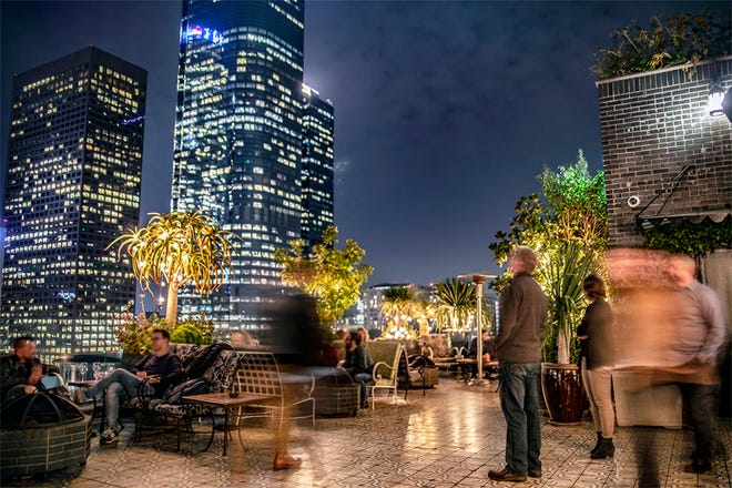 Nighttime photo of rooftop bar with the LA skyline in the background