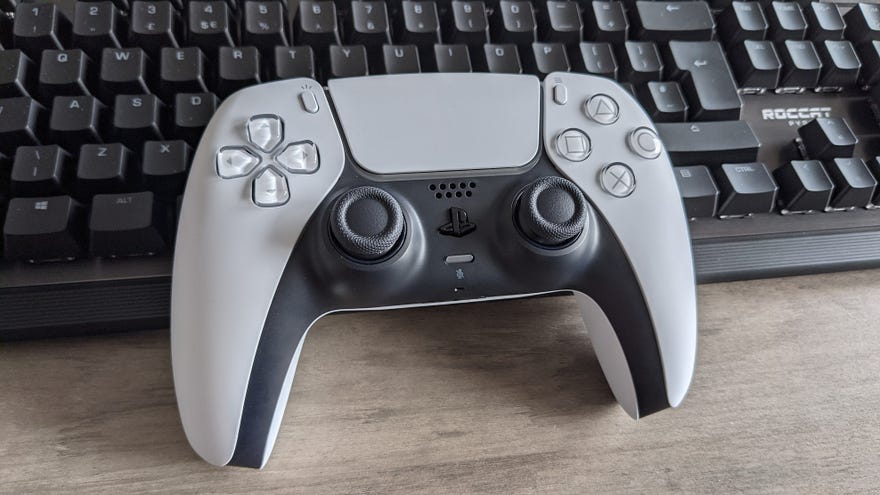 A PS5 controller sitting on top of a keyboard.