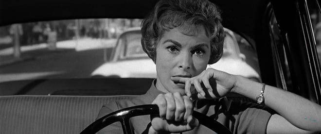 Still image from Psycho. Janet Leigh bites her finger as she drives, with a worried expression on her face.