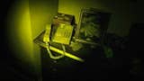 A house phone off the receive on a hallway table. The scene is dark and the phone is lit by a torchlight beam of some kind. A photo of a man's face stands next to the phone. It's a creepy scene.