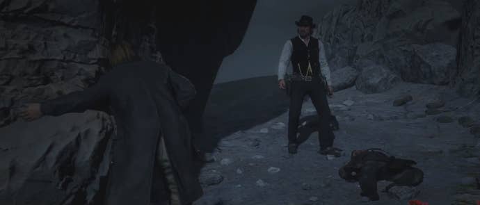 Два персонажа Red Dead Redemption 2 стоят в темной, каменистой местности во время финала игры.