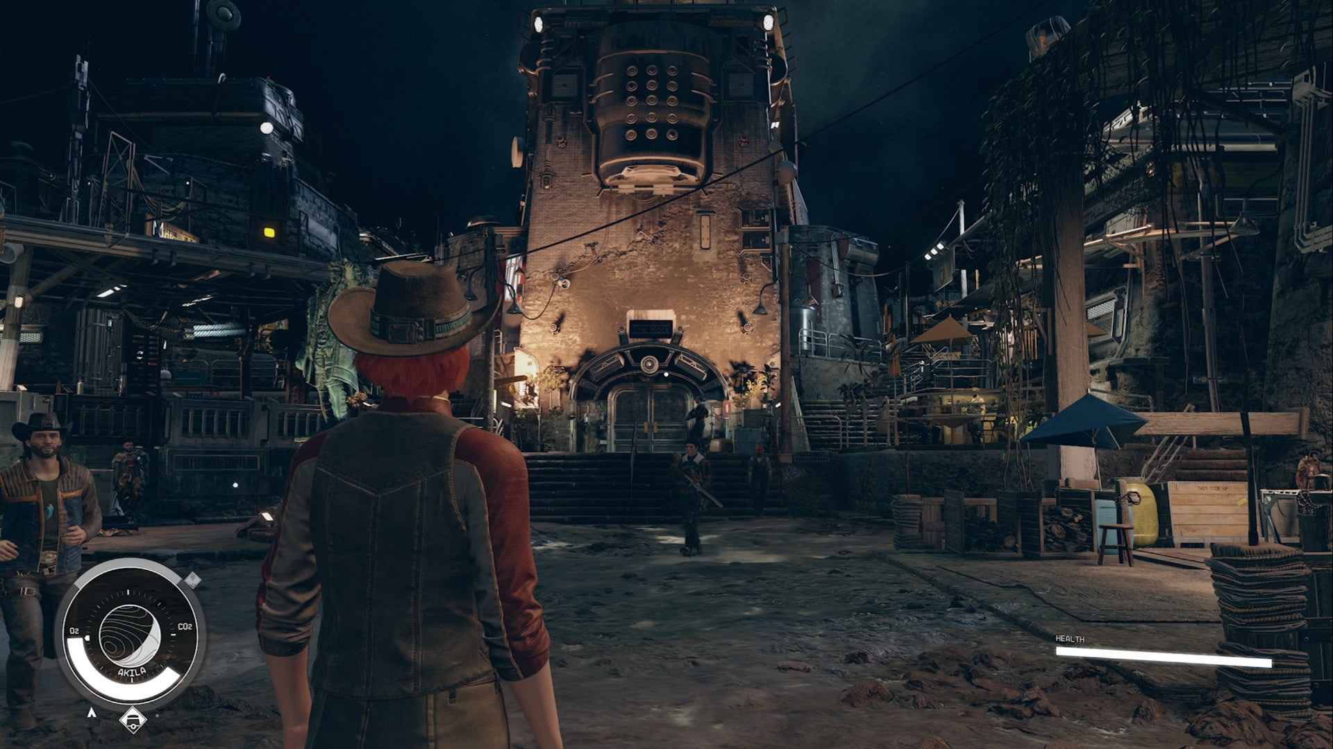 Starfield Akila City, un jugador con sombrero de vaquero está frente al edificio de roca en el medio de Akila por la noche
