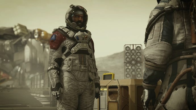 Barrett stands upright in his space suit and looks at the player character in Starfield.