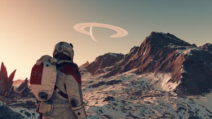 Une capture d'écran de Starfield montrant un astronaute debout dans un environnement montagneux et aride, regardant une planète aux anneaux visible dans le ciel brumeux.