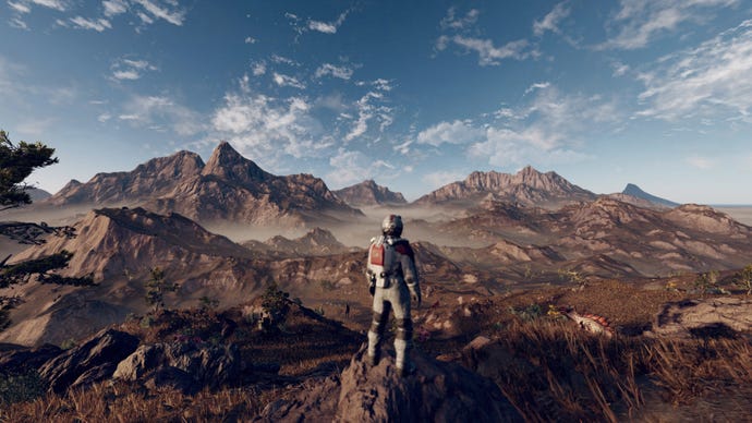 An explorer stands looking over a rocky planet in a Starfield screenshot.