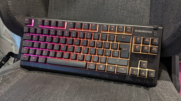 The SteelSeries Apex 3 TKL gaming keyboard on a chair.