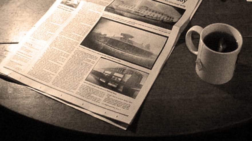A plain white mug of black tea or coffee, next to a broadsheet paper on a table, in black and white. It's the header for Sunday Papers!