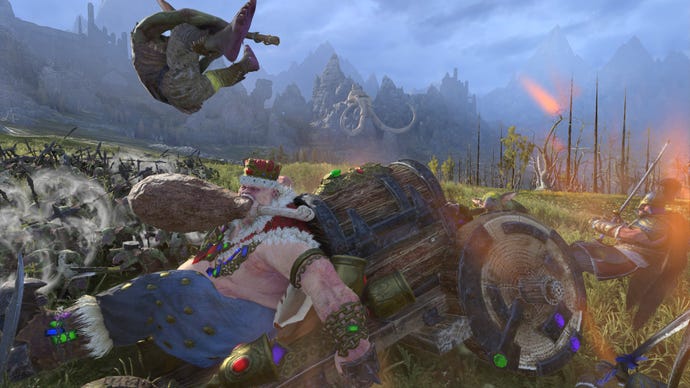 A screenshot of the ogre Greasus Goldtooth in Total War: Warhammer 3, a large, pink skinned monster with a giant turkey leg in his mouth even has he is pushed, topless, into war on a cart covered with treasure