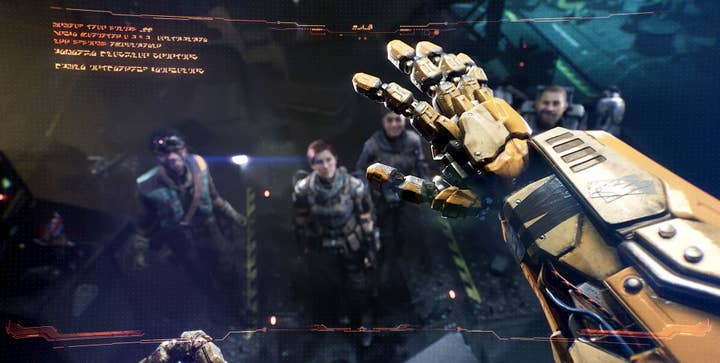 A first-person perspective from a Transformer focusing on its yellow metal hand and arm. Behind the arm are four out-of-focus humans in dark uniforms looking up at the robot