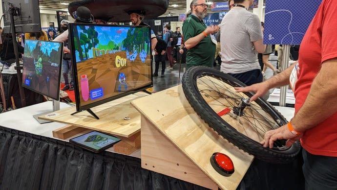 A man controls a game with a large bicycle wheel at GDC