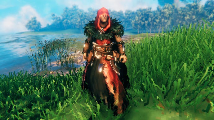 A player in Valheim stands on a Meadows coast and faces the camera wearing Eitr-Weave armour.