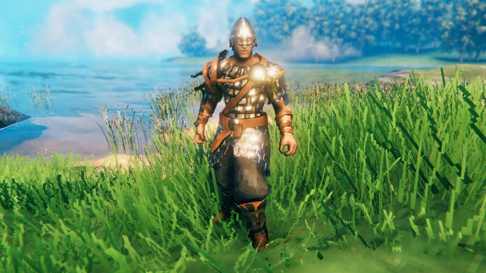 A player in Valheim stands on a Meadows coast and faces the camera wearing Iron armour.