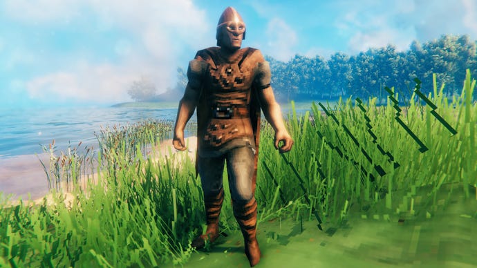 A player in Valheim stands on a Meadows coast and faces the camera wearing Leather armour.