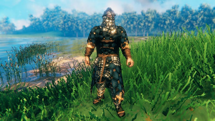 A player in Valheim stands on a Meadows coast and faces the camera wearing Padded armour.