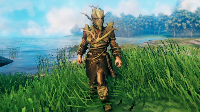 A player in Valheim stands on a Meadows coast and faces the camera wearing Root armour.