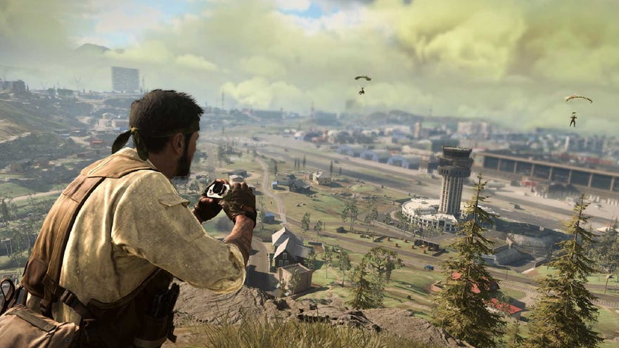 A screenshot of Woods staring out at 1980s Verdansk, binoculars in hand. Two players parachute into Airport in the distance.