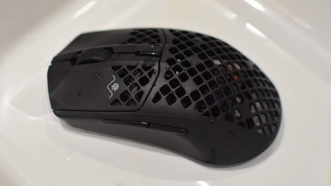 A SteelSeries Aerox 3 Wireless mouse covered in water droplets.