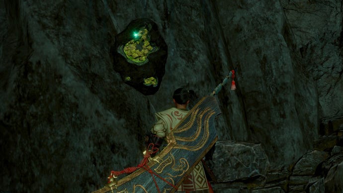 The player in Wild Hearts looks up at a Mirror Stone embedded in a cave wall.
