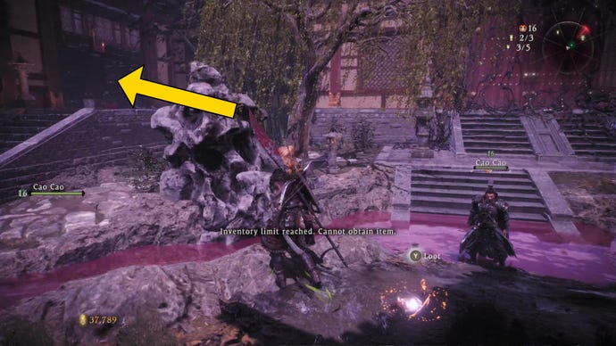 The player in Wo Long heads through a corrupted garden, following a path highlighted by a yellow arrow towards the nearest building.