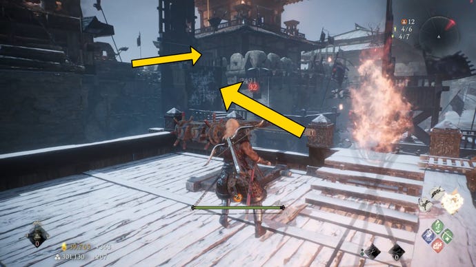 The player in Wo Long stands next to a Ballista in a snowy castle area, with arrows pointing in the direction of the castle wall.