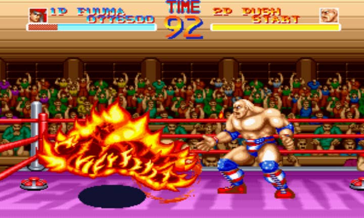 Picture of a World Heroes landmine deathmatch where one character in a wrestling ring is completely engulfed in flames. The opponent, a Hulk Hogan look-alike named Muscle Power, has a look of shock on his face