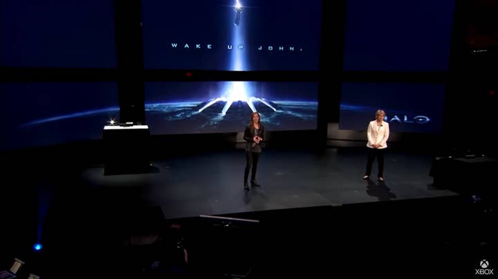 Bonnie Ross and Nancy Tellem on stage at the Xbox One reveal. On the screen behind them is an image from the Halo TV show with the words "Wake up John"