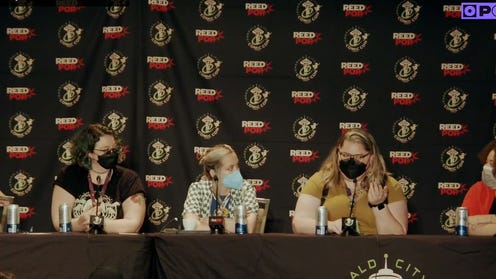 Photograph with Popverse logo featuring the panel sitting in front of a Reedpop Emerald City Comic Con backdrop