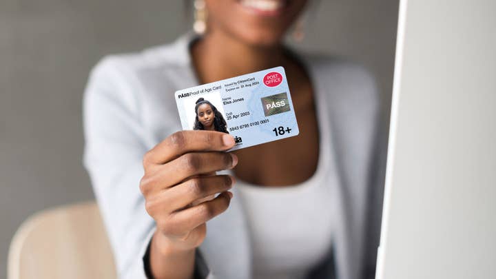 A picture of a dark-skinned woman holding up a photo ID card at the camera